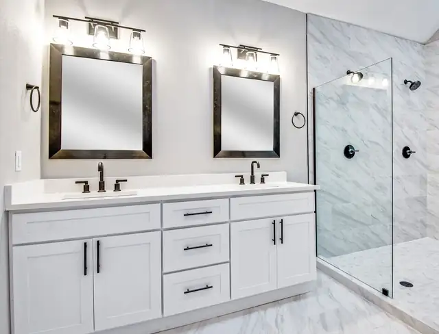 Temecula bathroom with white Shaker double vanity, black hardware, framed mirrors and a frameless glass shower in marble-look tile