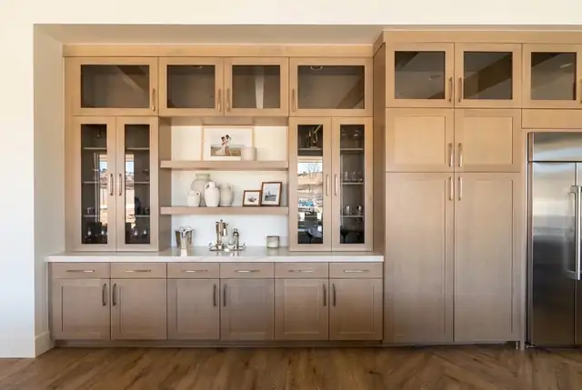 Built-in dining hutch and beverage center in Temecula with golden wood Shaker cabinets, glass doors and floating shelves