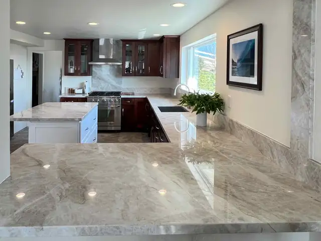 Kitchen with cherry cabinets, polished quartzite counters, a white island and a view window